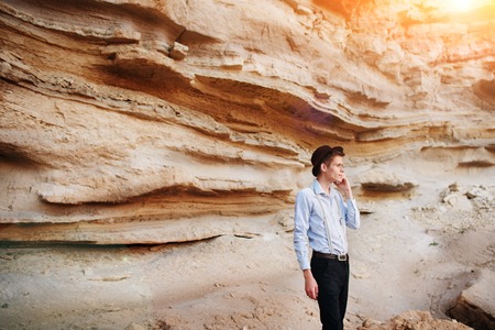Attractive man is standing in the middle of a sand quarry and making a call from a smartphone.の写真素材