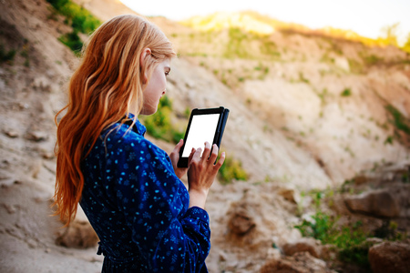Woman looking at the screen of a tablet on the background of a sand quarry.の写真素材