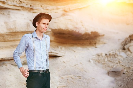 Stylish attractive man stands in the middle of a sand quarry and poses on the camera.の写真素材