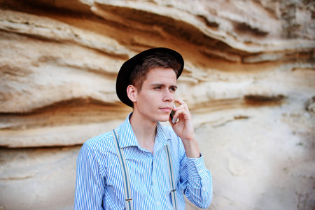 Attractive man is standing in the middle of a sand quarry and making a call from a smartphone.の写真素材