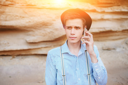 Attractive man is standing in the middle of a sand quarry and making a call from a smartphone.の写真素材