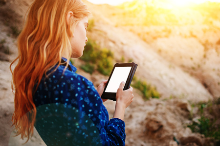 Woman looking at the screen of a tablet on the background of a sand quarry.の写真素材
