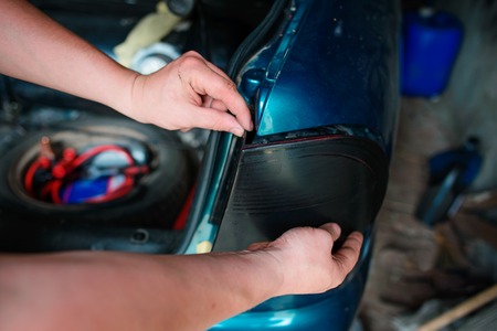 Closeup repairing of an broken blue car in garage by hands of machanic.の写真素材
