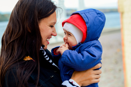 mother holding baby outdoors in fall seasonの写真素材