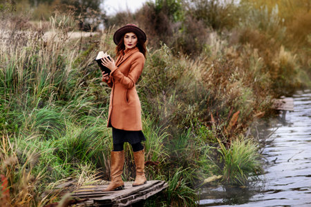 Girl-student sit on lawn and reads textbook.の写真素材