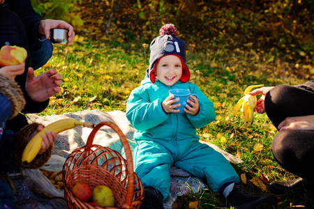 young boy drinks from a cup at a picnicの写真素材