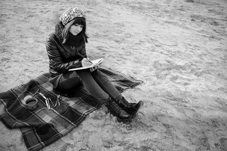 beautiful girl sitting on the beach and has records in a notebookの写真素材