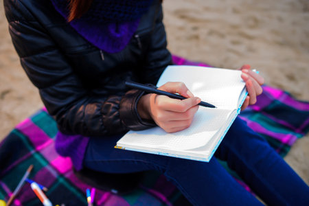 beautiful girl sitting on the beach and has records in a notebook, the appearance of the shoulder
