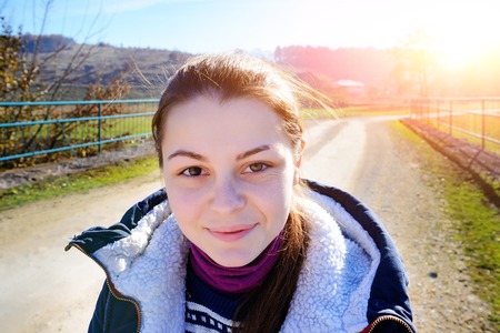 Portrait of a smiling beautiful young tourist woman with a different eye color on the background of the countryside.の写真素材
