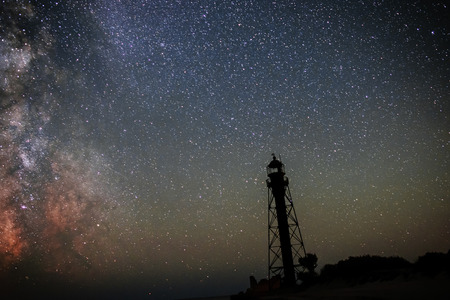 Silhouettes of the Old Lighthouse sandy beach and ocean against the background of the starry sky.の写真素材