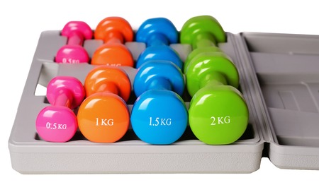 A set of colored isolated dumbbells for sports on a white background is stacked in a gray case.の写真素材