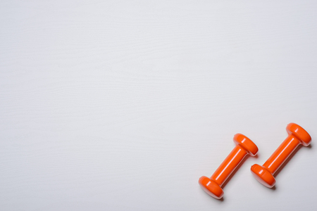 Two dumbbells of orange are lying on a white background with a tree texture.の写真素材