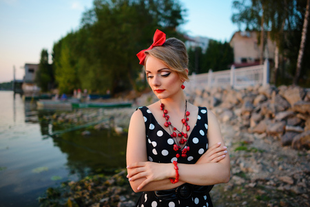 A beautiful young woman dressed standing by the lake.の写真素材