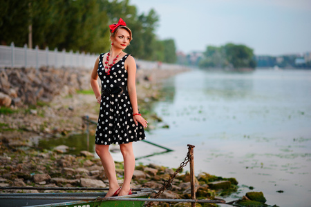 A beautiful young woman dressed standing by the lake, on the background of the sunset.の写真素材