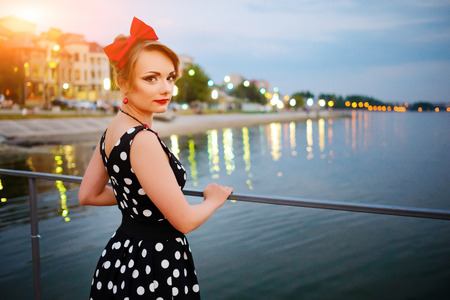 A beautiful young woman dressed stand on the pier in the evening.の写真素材