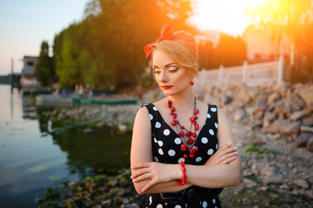 A beautiful young woman dressed standing by the lake.の写真素材