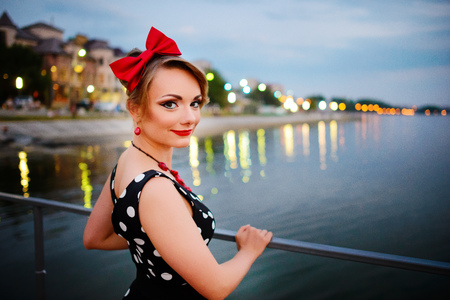 A beautiful young woman dressed stand on the pier in the evening.の写真素材
