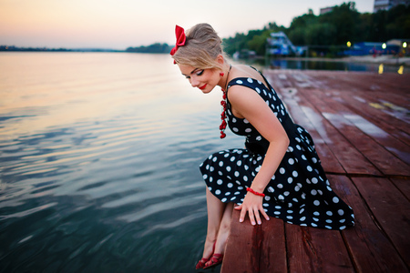 A beautiful young woman dressed sitting on the pier.の写真素材