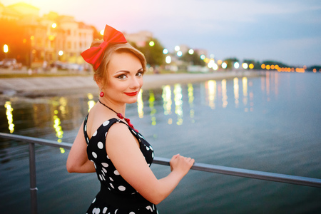 A beautiful young woman dressed stand on the pier in the evening.の写真素材