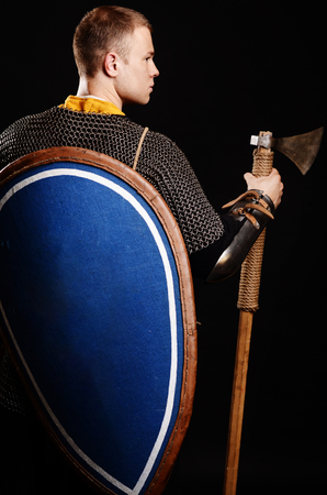 Warrior Stand his back to the camera with a shield on his back and an ax in his hands.の写真素材