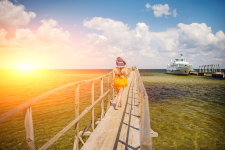 girl in a blue hat goes along the pier.の写真素材