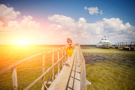 girl in a blue hat goes along the pier.の写真素材