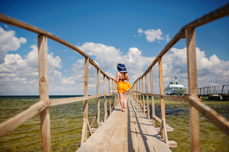 girl in a blue hat goes along the pier.の写真素材
