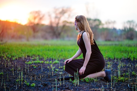 Young beautiful woman with purple shine on her face standing on the grass and looking at the back.の写真素材
