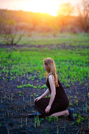 Young beautiful woman with purple shine on her face standing on the grass and looking at the back.の写真素材