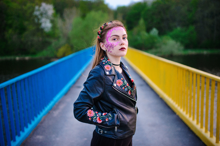 A young beautiful woman with a violet shine on her face standing on the bridge.の写真素材