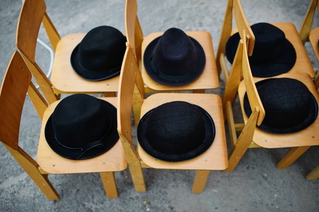 Many black retro hats lie on wooden chairs.の写真素材