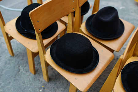 Many black retro hats lie on wooden chairs.の写真素材