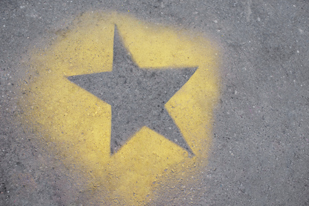 the yellow star is painted on gray asphalt.の写真素材