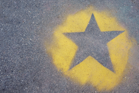 the yellow star is painted on gray asphalt.の写真素材
