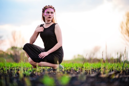 A young beautiful woman with a violet shine on her face stands near a burnt tree.の写真素材