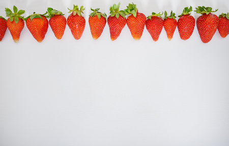 strawberry fruits in a row on white wood table background.の写真素材