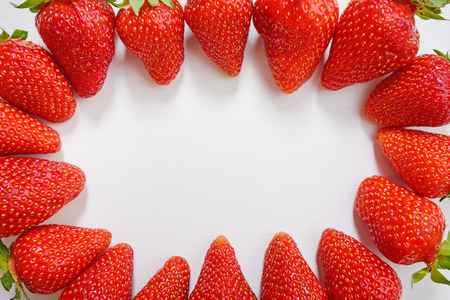 Circle made of fresh tasty strawberry on white wooden background.の写真素材