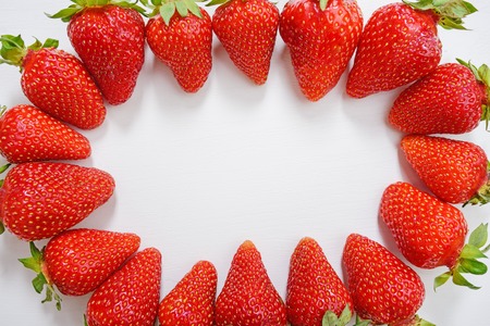 Circle made of fresh tasty strawberry on white wooden background.の写真素材