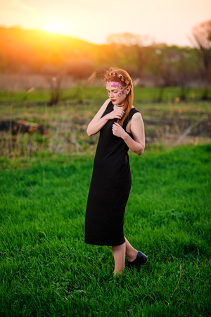 A young beautiful woman with a violet shine on her face stands on the grass.の写真素材
