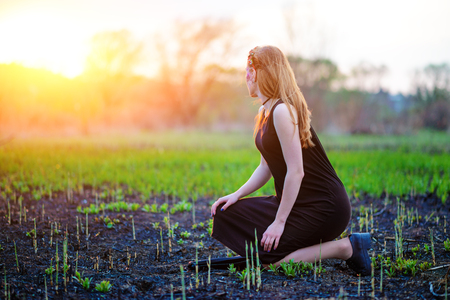 Young beautiful woman with purple shine on her face standing on the grass and looking at the back.の写真素材