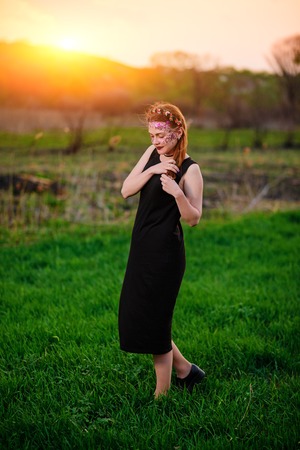 A young beautiful woman with a violet shine on her face stands on the grass.の写真素材