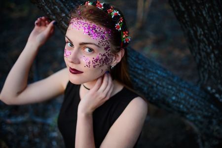 A young beautiful woman with a violet shine on her face stands near a burnt tree.の写真素材