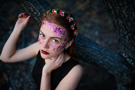 A young beautiful woman with a violet shine on her face stands near a burnt tree.の写真素材