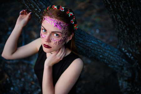 A young beautiful woman with a violet shine on her face stands near a burnt tree.の写真素材