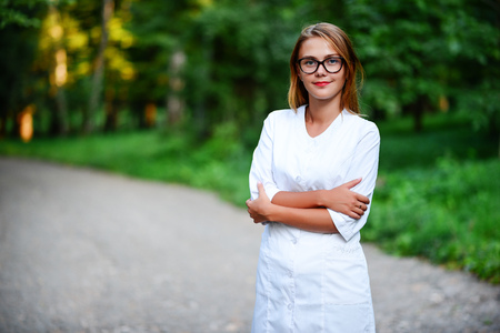 a young girl who is a doctor stands outside, hands are crossed on the stomach.の写真素材
