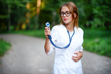a young girl who is a doctor stands outside, holds the left hand on the belly.の写真素材
