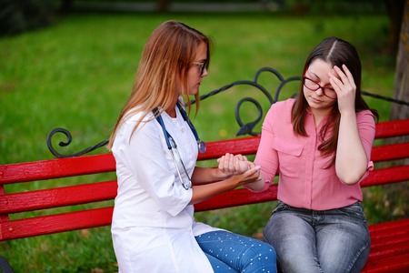 caring doctor or nurse taking young patient outdoors, The patient is worried about headacheの写真素材