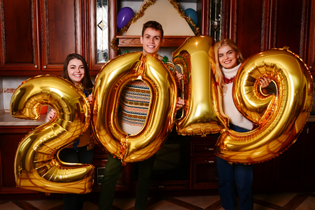 New 2019 Year is coming. Group of cheerful young people carrying gold colored numbers and have fun at the party.の写真素材