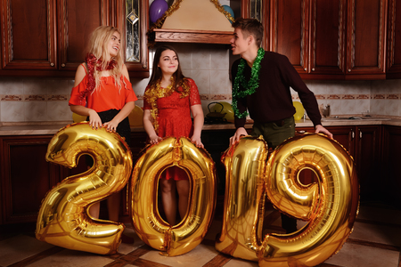 New 2019 Year is coming. Group of cheerful young people carrying gold colored numbers and have fun at the party.の写真素材