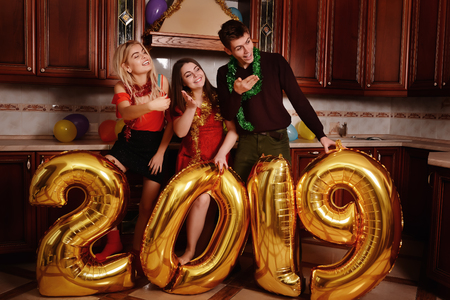 New 2019 Year is coming. Group of cheerful young people carrying gold colored numbers and have fun at the party.の写真素材